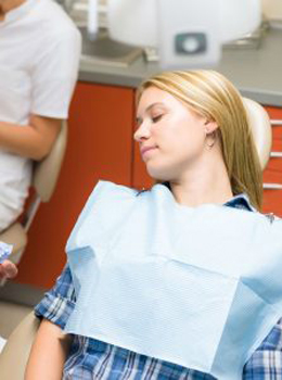 Photo of a young woman who has received sedation dentistry and is relaxing in the chair during treatment.