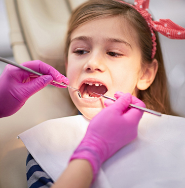 Young girl at dental office with dental instruments in her mouth