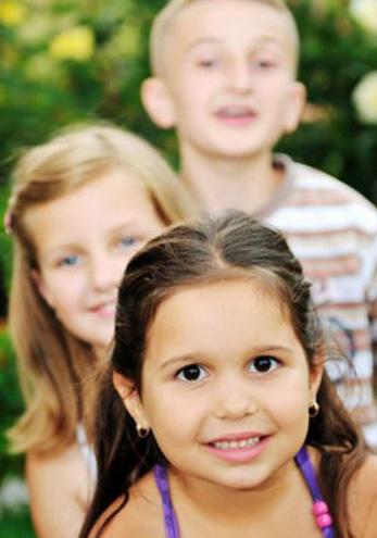 Three kids standing one behind another, for informatio on a snap-on smile for children