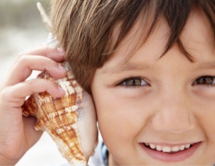 Young boy with a seashell - for info on cavities in primary teeth and dental anxiety in children