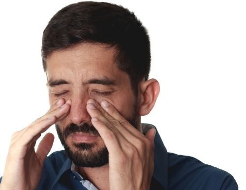 Man with hands near his nose portraying sinus pressure after wisdom teeth removal