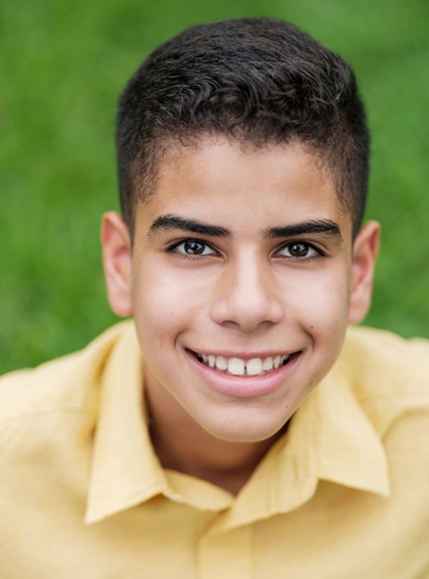 Young Hispanic boy smiling, portraying pediatric cosmetic dentistry on broken frot teeth